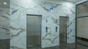 Un ascensor moderno con paredes de mármol y una pantalla digital.