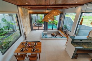 Eine moderne Küche mit Essbereich, großen Fenstern und Blick ins Freie.