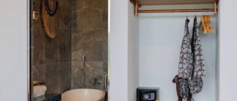 A modern bathroom with a freestanding bathtub, a wooden shelf with towels, and a wall-mounted air conditioner.