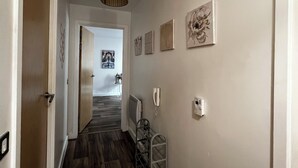Un pasillo con piso de madera, una lámpara en el techo y una puerta al final.