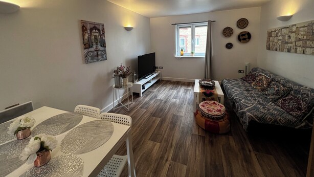 Una sala de estar con televisor, sofá, mesa de comedor y objetos decorativos.