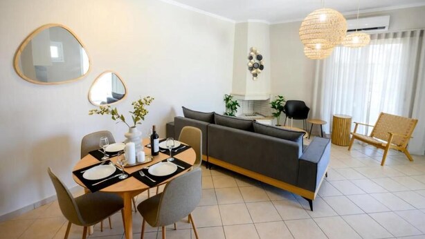 Un comedor moderno con una mesa lista para dos personas, un sofá y un sillón.