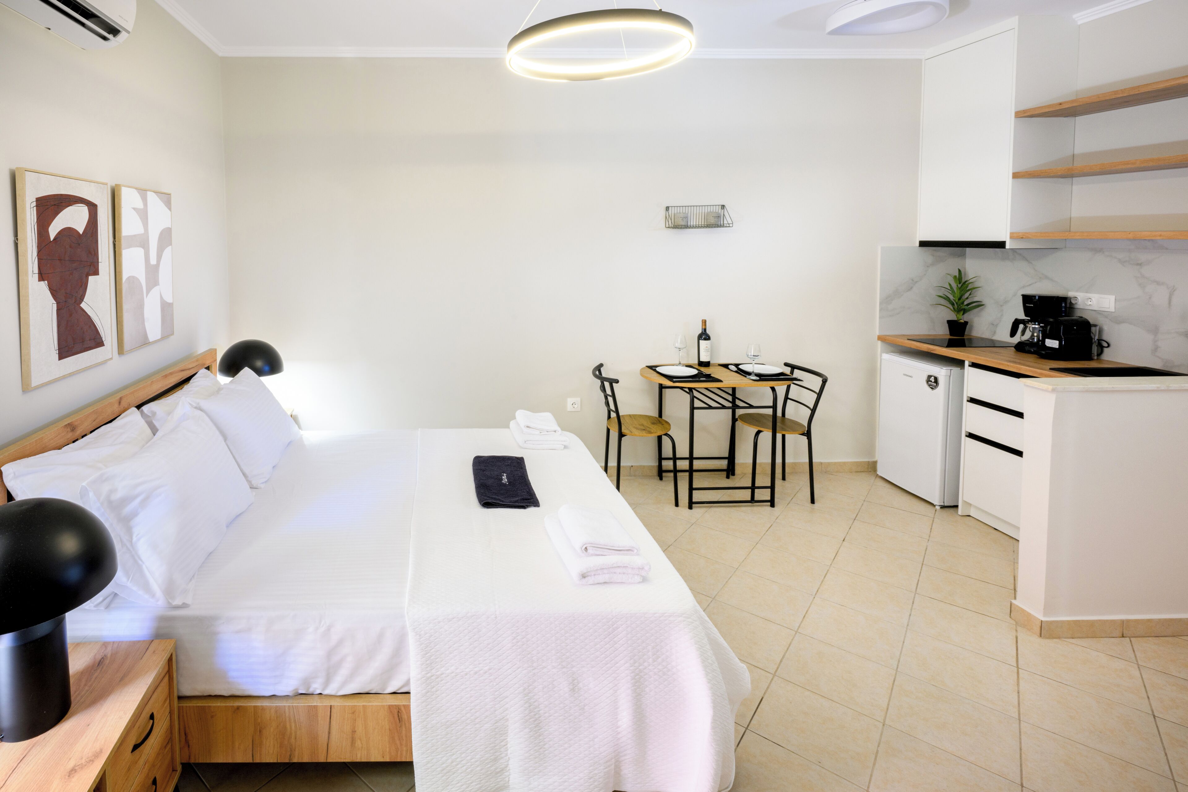 Un dormitorio con cama, mesita de noche y un pequeño escritorio con sillas.