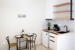 Eine kompakte Küche mit Esstisch, Stühlen, einer Kaffeemaschine und einem kleinen Kühlschrank.