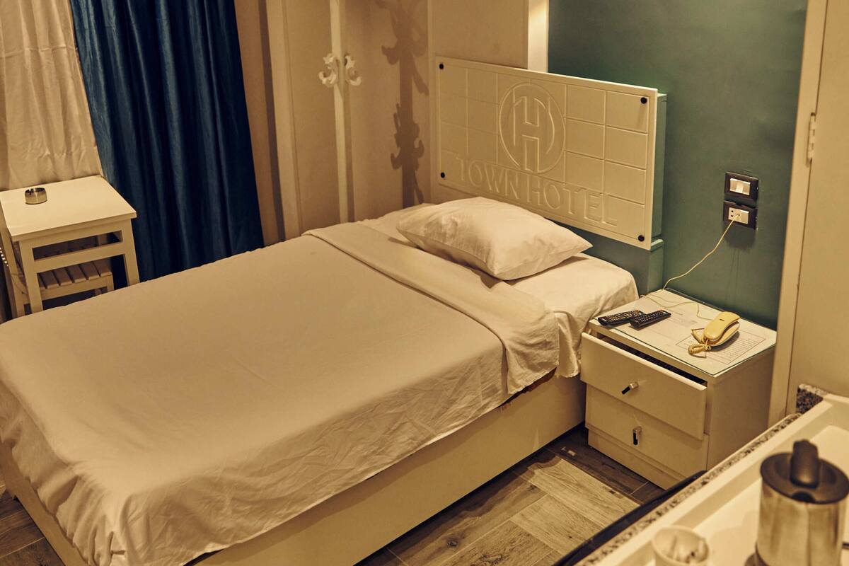 Una habitación de hotel con cama, mesita de noche y cafetera.