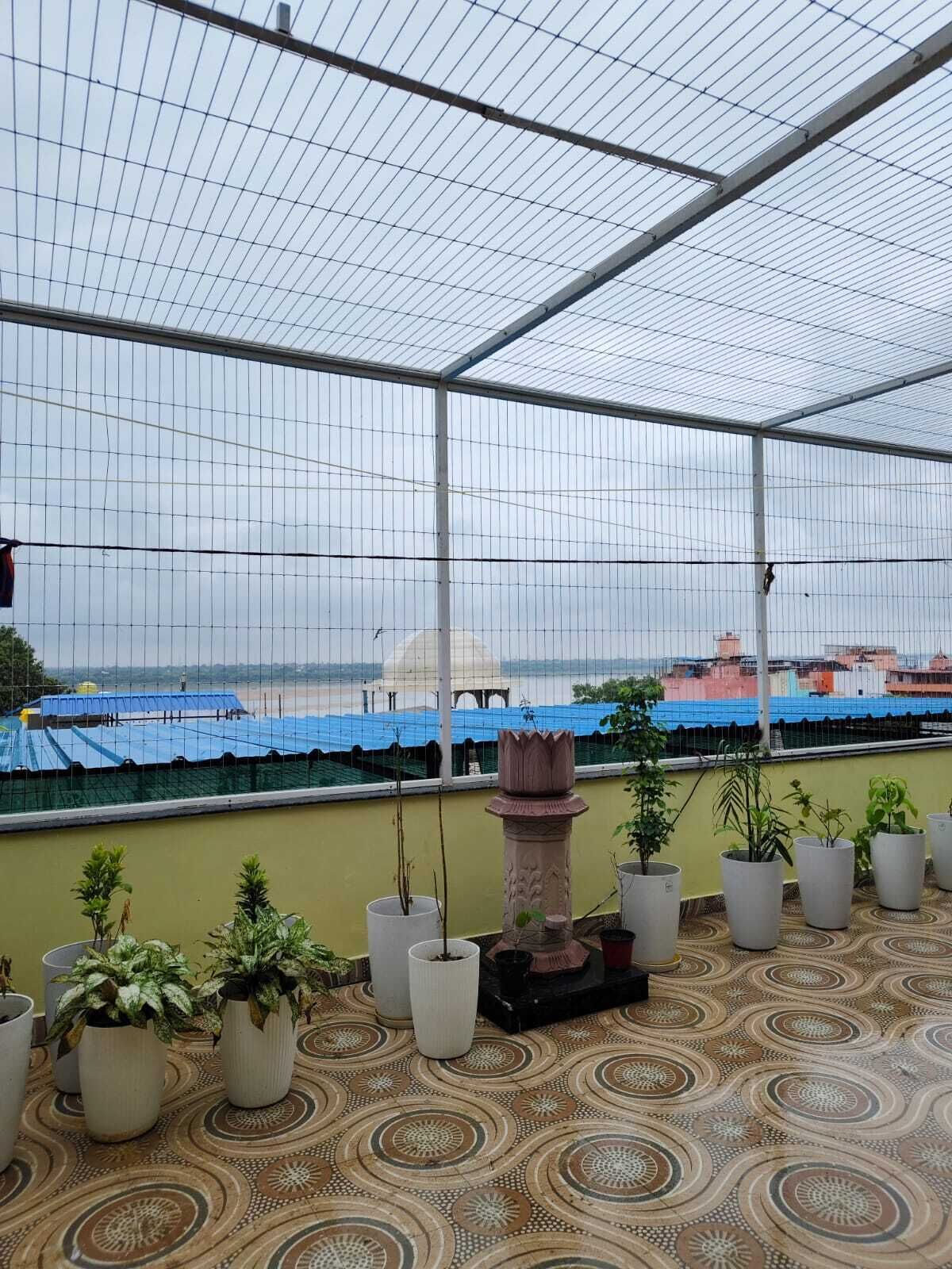 A covered outdoor area with a patterned floor, potted plants, and a view of buildings in the background.