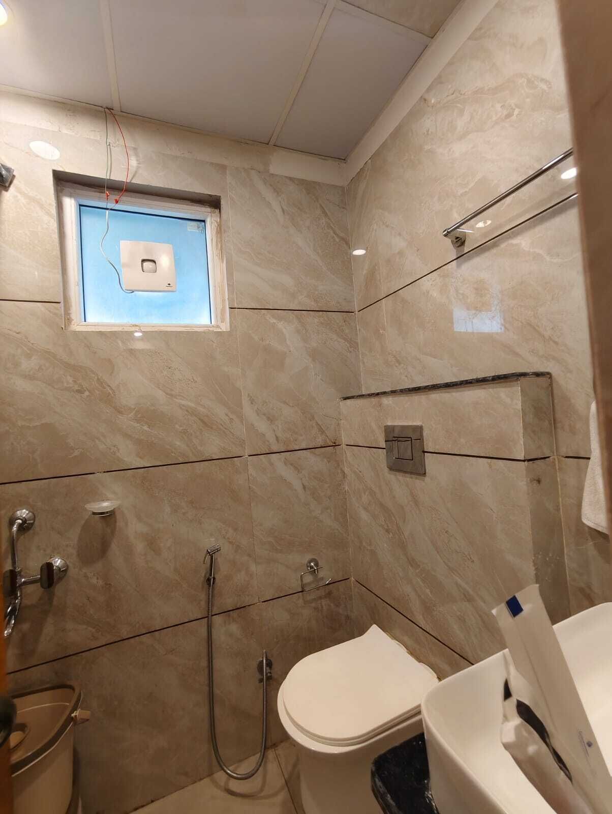 A bathroom with a toilet, shower, and a window.