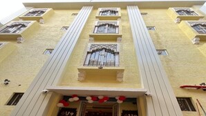 A multi-story building with a central entrance, a staircase leading to the entrance, and a banner with the text '2016 HAPPY NEW YEAR'. - Atithi Sevalay (Varanasi)