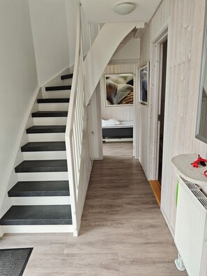 Eine Treppe führt zu einem Schlafzimmer mit einem Bett, einem Nachttisch und einem an der Wand montierten Fernseher.