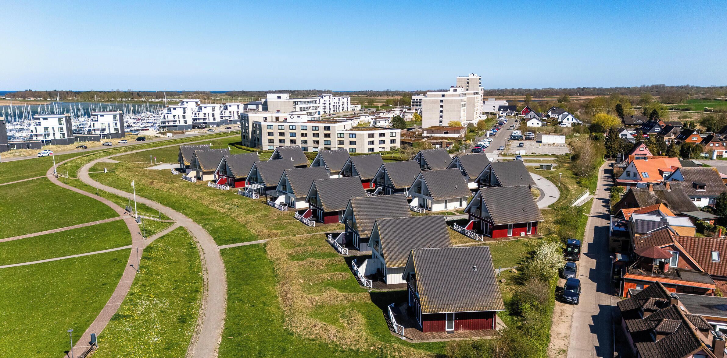 Ett bostadsområde med moderna hus, en småbåtshamn och en stor byggnad med flera våningar.