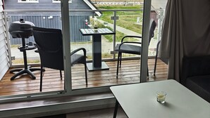 Quarto com vista para uma casa, uma churrasqueira e uma mesa com uma vela.