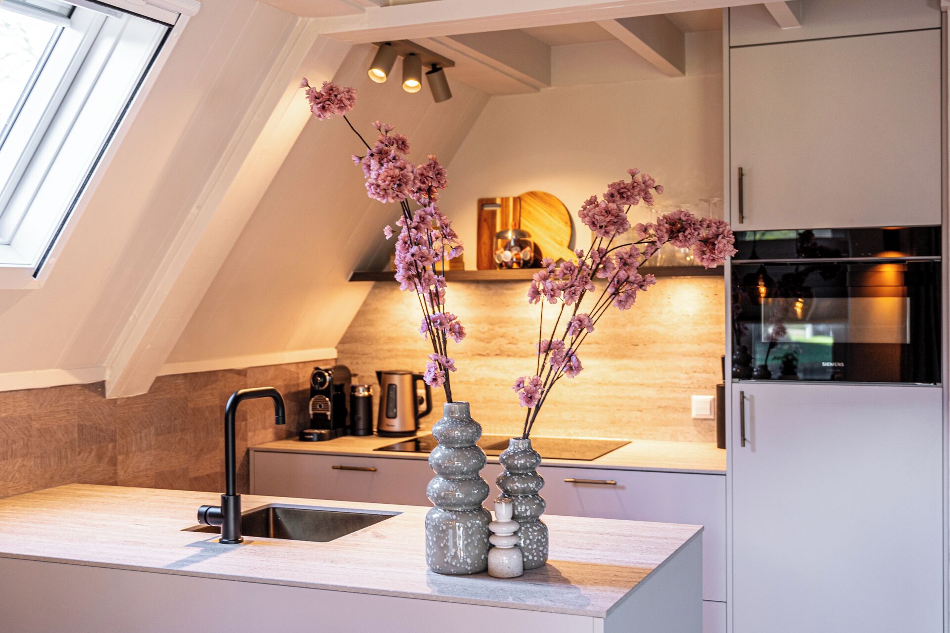 Een moderne keuken met een dakraam, een spoelbak en decoratieve vazen.