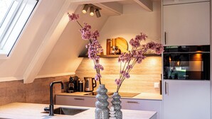 A modern kitchen with a skylight, a sink, and decorative vases. - Casa Vida Verde - Luxury cottage by water & nature (Gramsbergen)