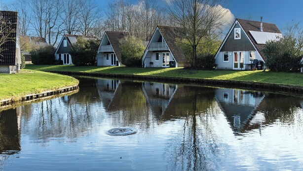 A canal with houses on one side and trees on the other. - Casa Vida Verde - Luxury cottage by water & nature (Gramsbergen)