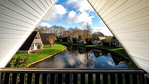 A triangular view of a canal with houses on one side and a clear sky above. - Casa Vida Verde - Luxury cottage by water & nature (Gramsbergen)