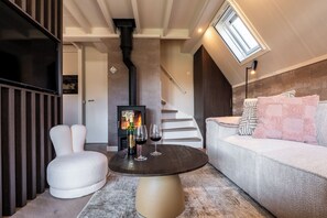 Een moderne woonkamer met een open haard, een ronde tafel, een bank en een trap.