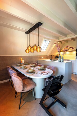 Een eetruimte met een ronde tafel, stoelen en een keuken op de achtergrond.