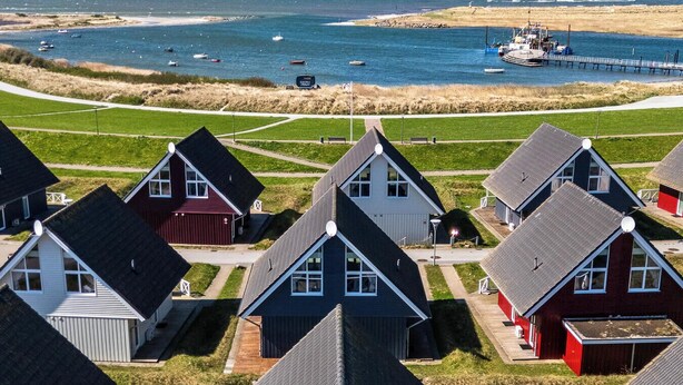 A coastal housing development with uniform houses, a pier, and boats in the background. - "Strandgut" Marina Wendtorf holiday home by the beach with sea view (Wendtorf)