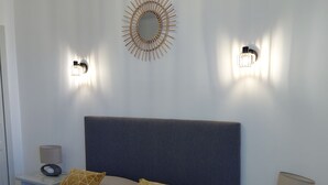 Ein Schlafzimmer mit einem Bett, zwei Nachttischen, einem Wandspiegel und zwei Wandleuchten.
