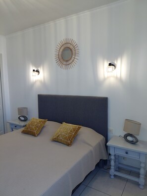 A bedroom with a bed, two bedside tables, a wall-mounted mirror, and two wall sconces. - House T4 center Bastia - terrace, comfort and ideal location (BASTIA)
