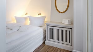 Ein Schlafzimmer mit einem Bett, Nachttischlampen, einem Spiegel und einer Heizung.