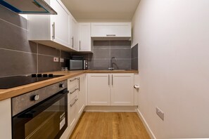 Una cocina compacta con estufa, horno, microondas y pileta.