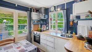 Une cuisine équipée d’une cuisinière, d’un four, d’un évier et d’une fenêtre avec des rideaux.