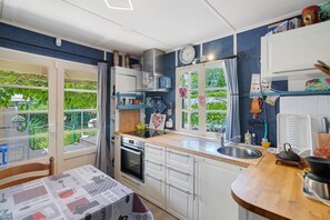 Eine Küche mit Herd, Backofen, Spüle und einem Fenster mit Vorhängen.