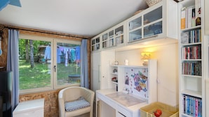 Une chambre d’enfant avec un bureau, une chaise, une bibliothèque et une fenêtre donnant sur un jardin.