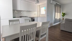 A modern kitchen with white cabinets, a dining table with chairs, and a large window. - Charming El Paraiso Apt with Gibraltar Views Near Puerto Banus (El Paraíso)