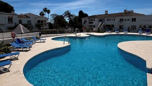A swimming pool with blue water, surrounded by lounge chairs and a tiled deck. - Charming El Paraiso Apt with Gibraltar Views Near Puerto Banus (El Paraíso)