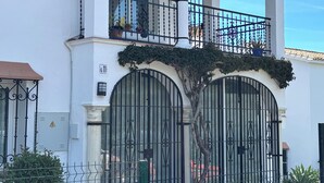 A white building with arched balconies, a gated entrance, and a clear sky. - Charming El Paraiso Apt with Gibraltar Views Near Puerto Banus (El Paraíso)
