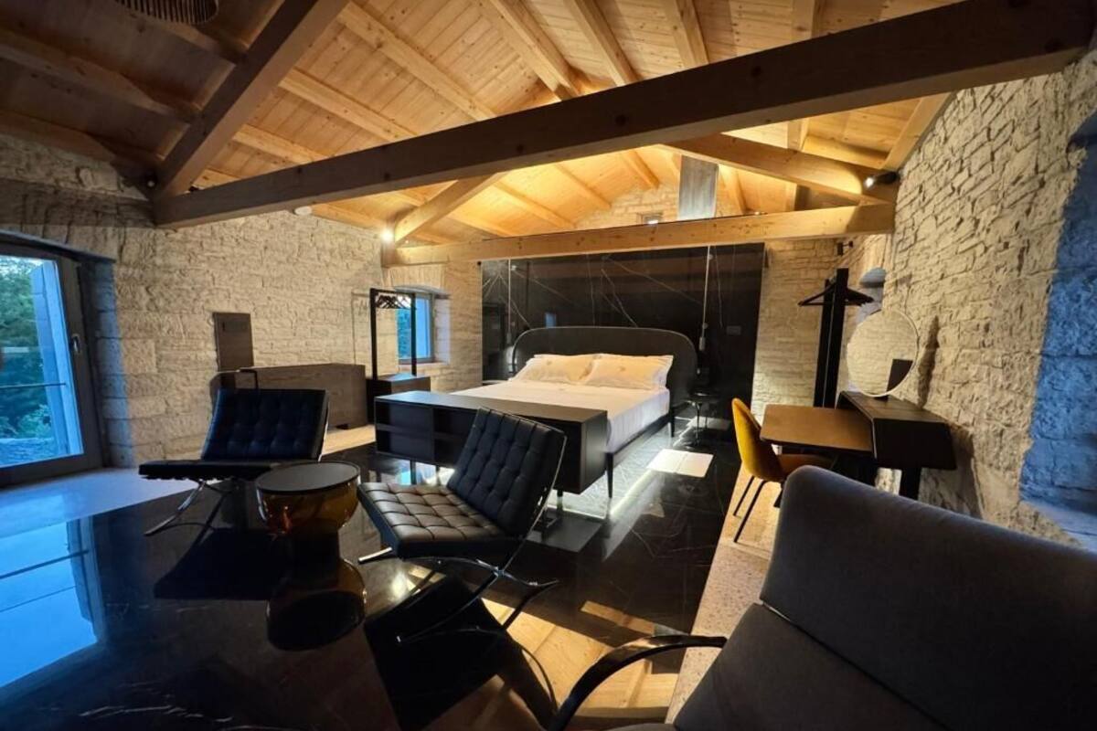 Un dormitorio moderno con una cama, una mesita de cristal y una silla.
