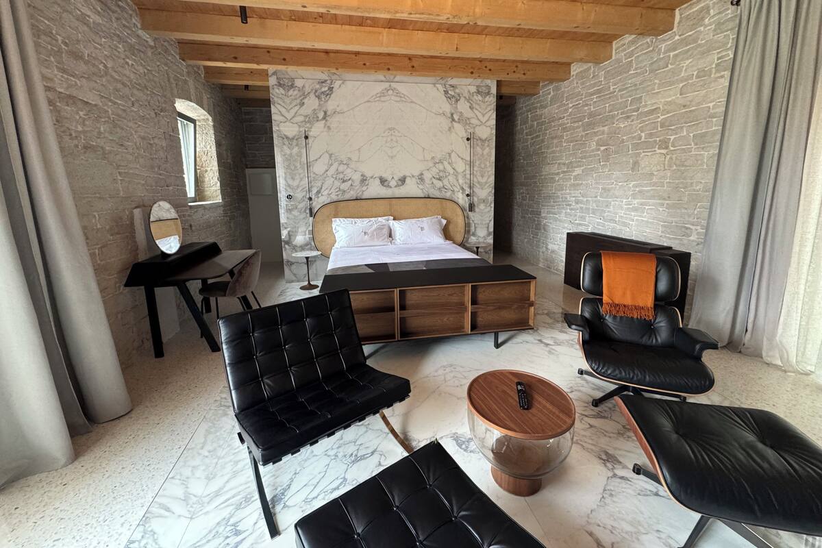 Un dormitorio con cama, escritorio, silla, sofá y mesa de centro.