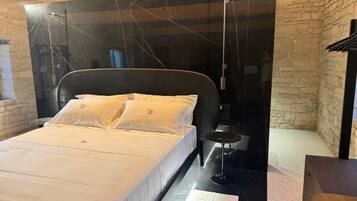 Un dormitorio con cama, una mesita y una lámpara colgante.