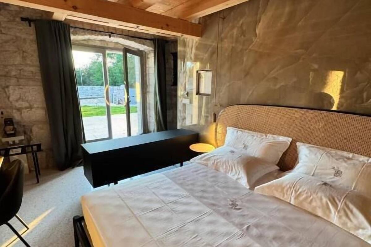 Un dormitorio con cama, escritorio y ventana con cortinas.