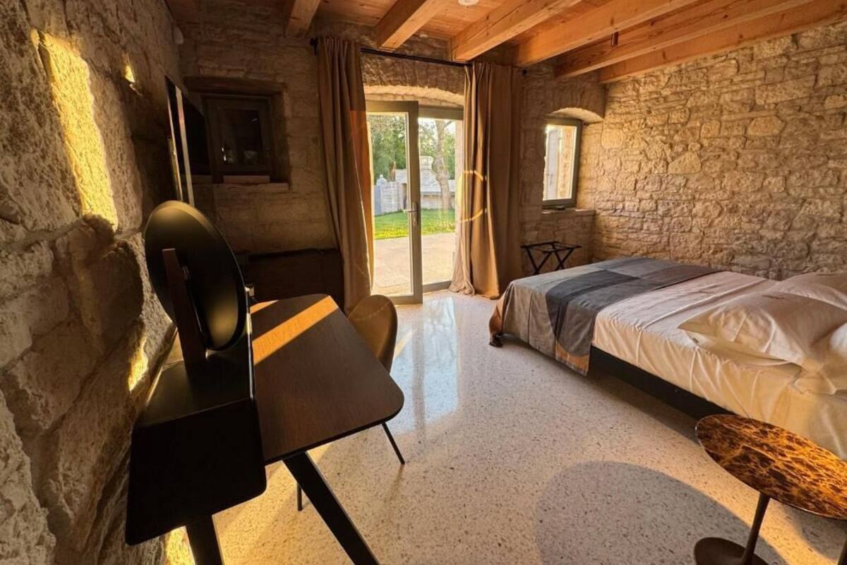 Una habitación acogedora con cama, escritorio y silla, paredes de piedra y ventana.