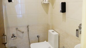 Un bagno piccolo con il water, una doccia, un lavandino, un cestino e un portascopevoli.