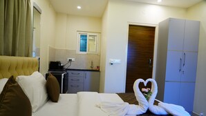 Una camera d'albergo con un letto, un armadio, un angolo cottura e un bagno parzialmente visibile attraverso una porta aperta.