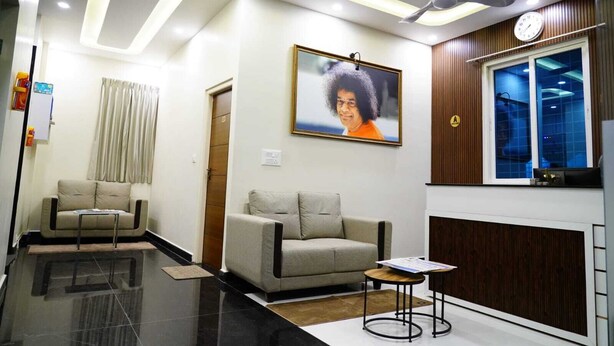 Un'area d'attesa moderna con una ventola a soffitto, un orologio, un quadro incorniciato e due divani.