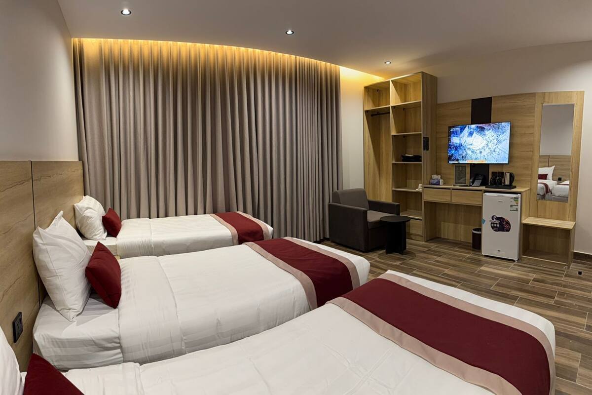 Habitación de hotel con dos camas, un escritorio, televisor y minibar.