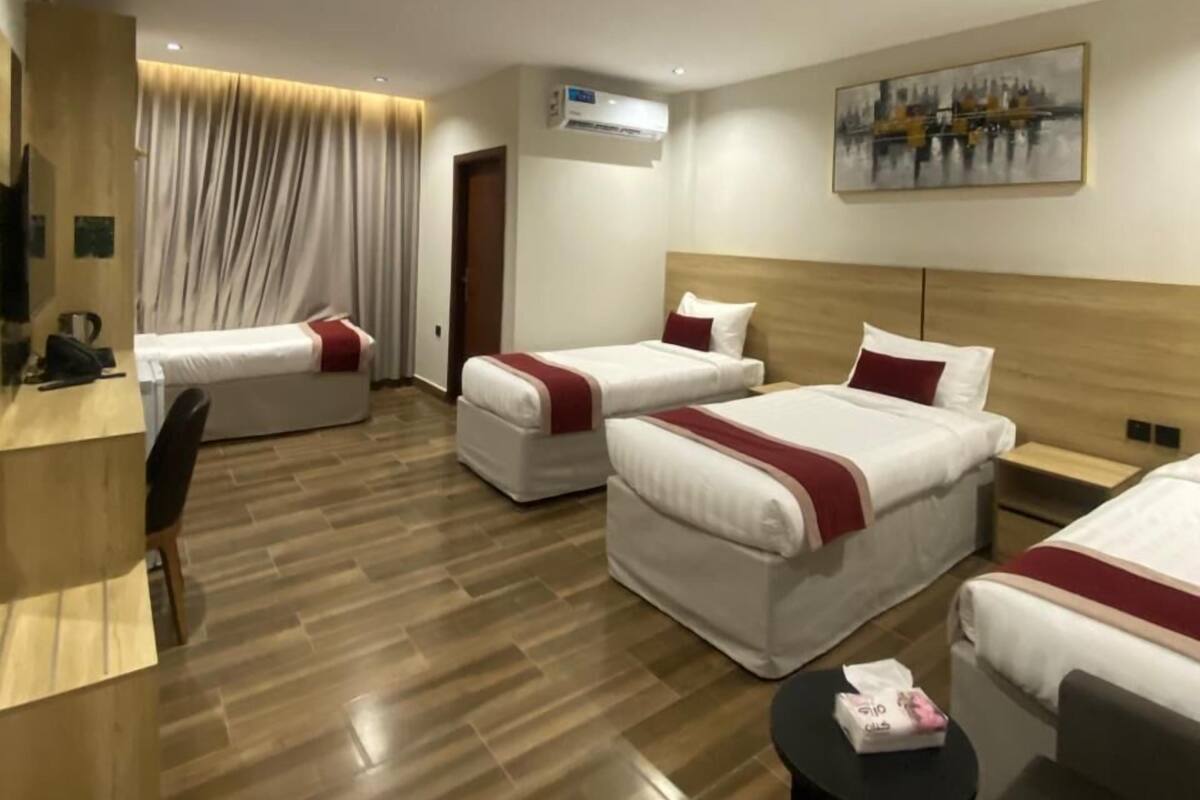 Habitación de hotel con dos camas, un escritorio, una silla, una mesita y un cuadro en la pared.