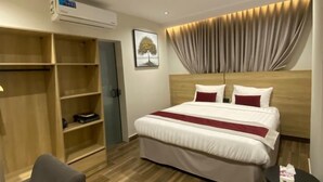Et hotelværelse med seng, garderobeskab, skrivebord og aircondition.