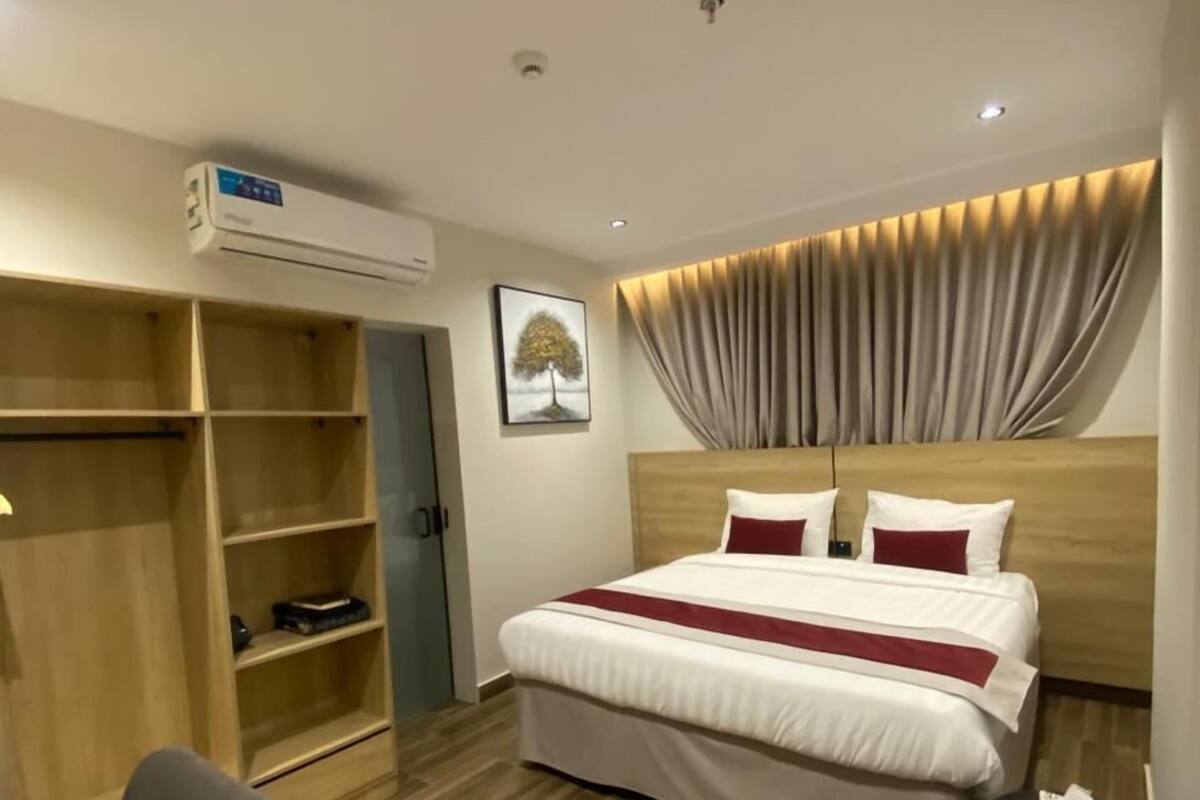 Una habitación de hotel con cama, armario, escritorio y aire acondicionado.