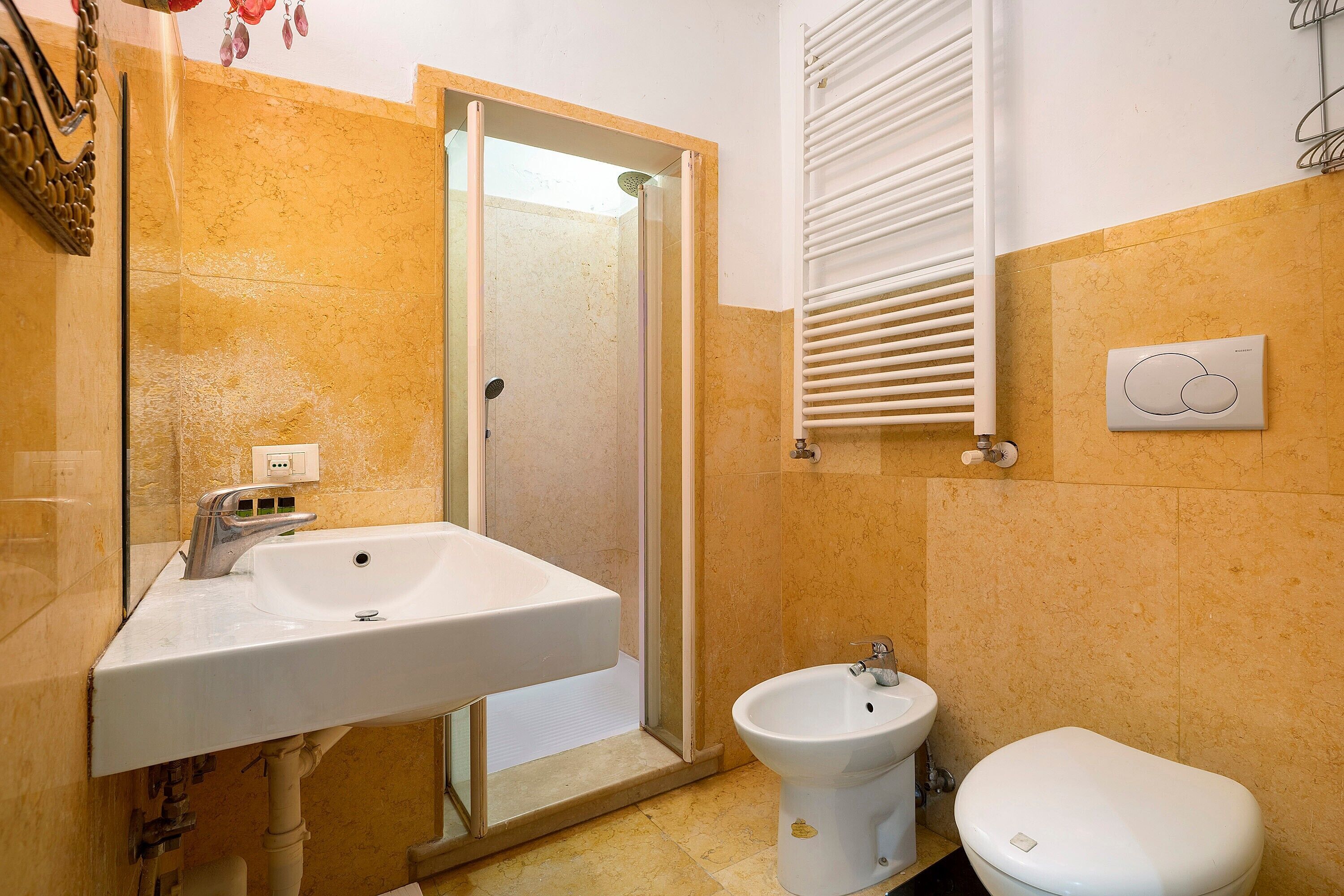 A bathroom with a sink, bidet, toilet, and a shower door.