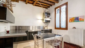 A modern kitchen with a dining area, stainless steel appliances, and a red patterned rug. - Cà Leon, Artist’s Loft in the Heart of the City (Venezia)