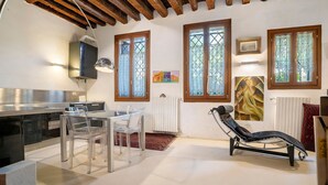 A kitchen with a dining area, a reclining chair, and artwork on the walls. - Cà Leon, Artist’s Loft in the Heart of the City (Venezia)