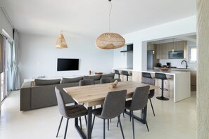 A modern living space with a dining area, kitchen, and seating arrangement. - Elegant seafront 2BR apartment, stunning sea views, just steps to shore! (Oropioi)