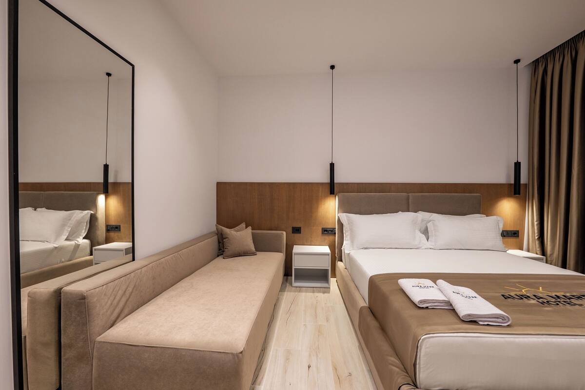 Una habitación de hotel con una cama, un banco, una mesita de noche y un espejo.