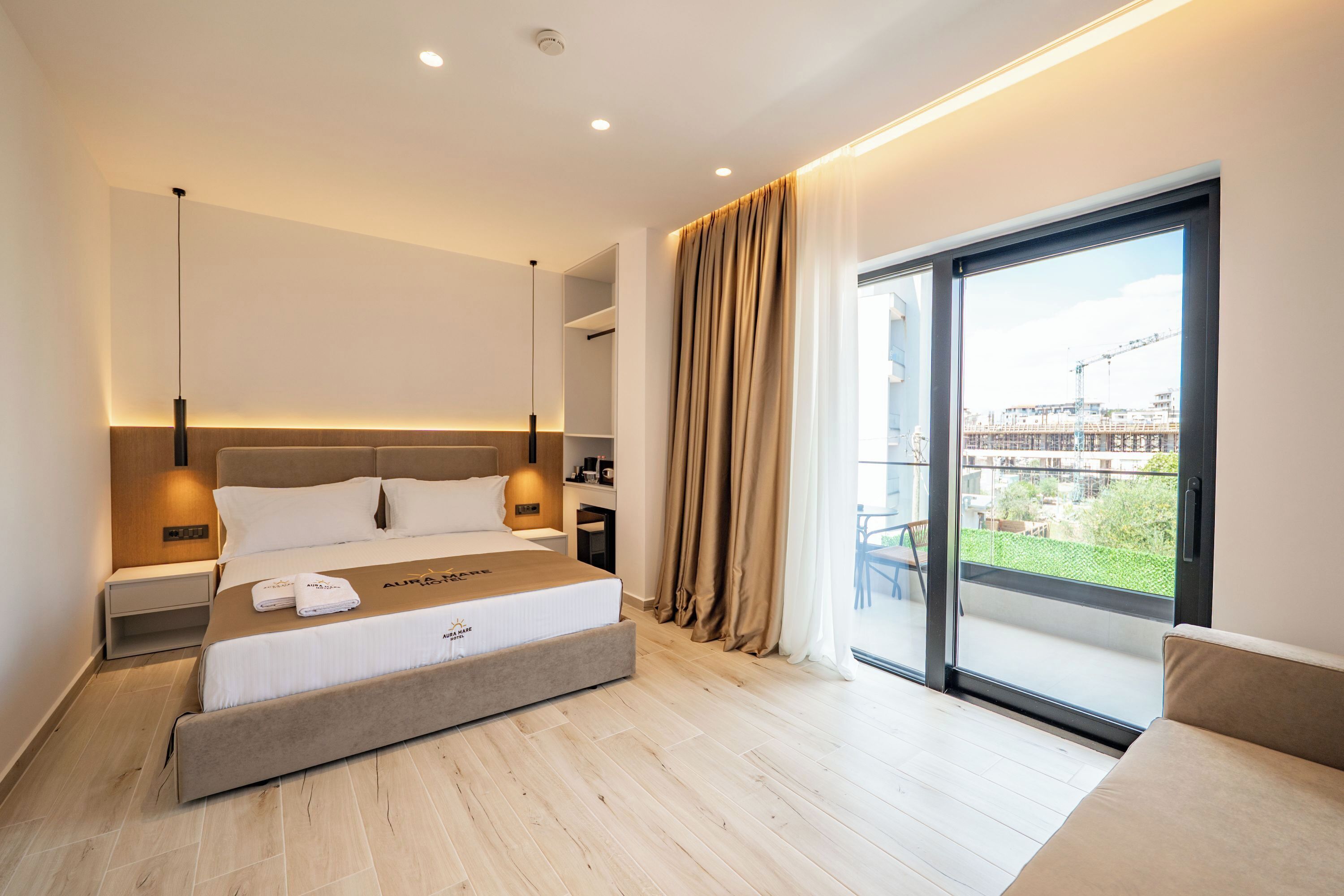 Habitación de hotel moderna con una cama grande, mesitas de noche, y vistas al exterior a través de un ventanal corredero, además de un balcón.